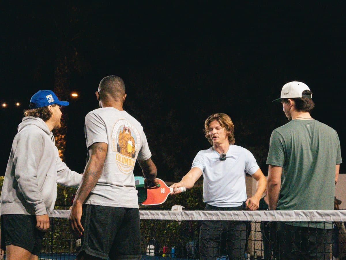 A group of pickleball players tapping paddles at the net after a match